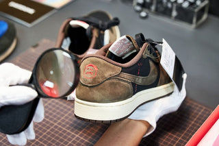 A professional inspecting and verifying a pair of Jordan 1 low x Travis Scott