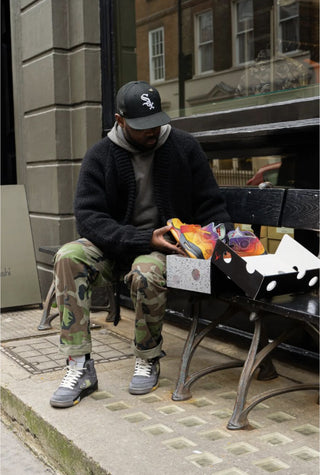 London Sneaker Club Moses, wearing a pair of Jordan off white 5's inspecting a customised pair of the same sneakers